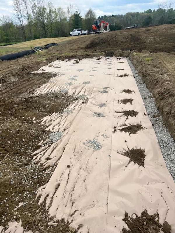 Construction site with a fabric sheet covered in dirt and gravel, prepared for building.
