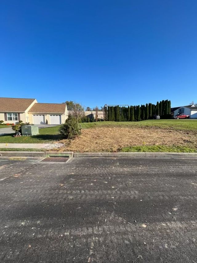 Cleared lot for construction with a row of trees in the background under a blue sky.