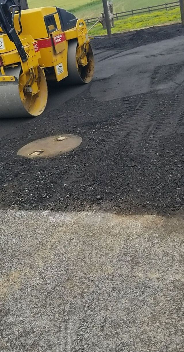 Yellow asphalt roller compacting fresh black asphalt on a road.