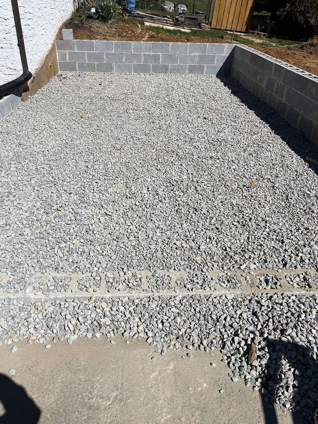Gravel-filled rectangular space bordered by cinder blocks, likely a foundation prep.