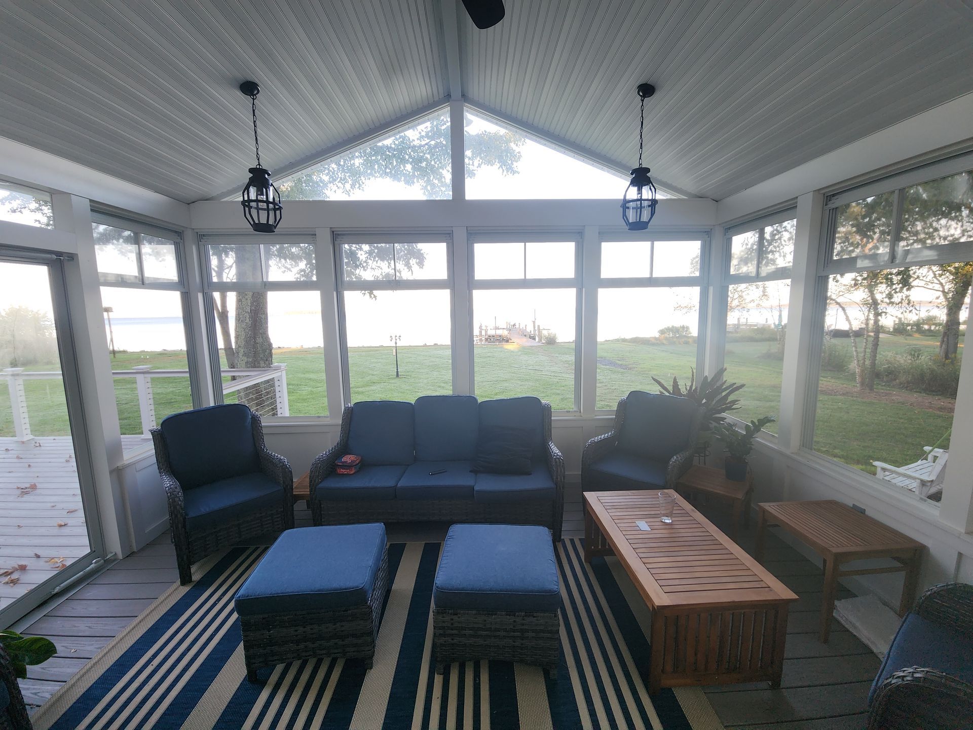 Sunroom with blue furniture, striped rug, and water view.