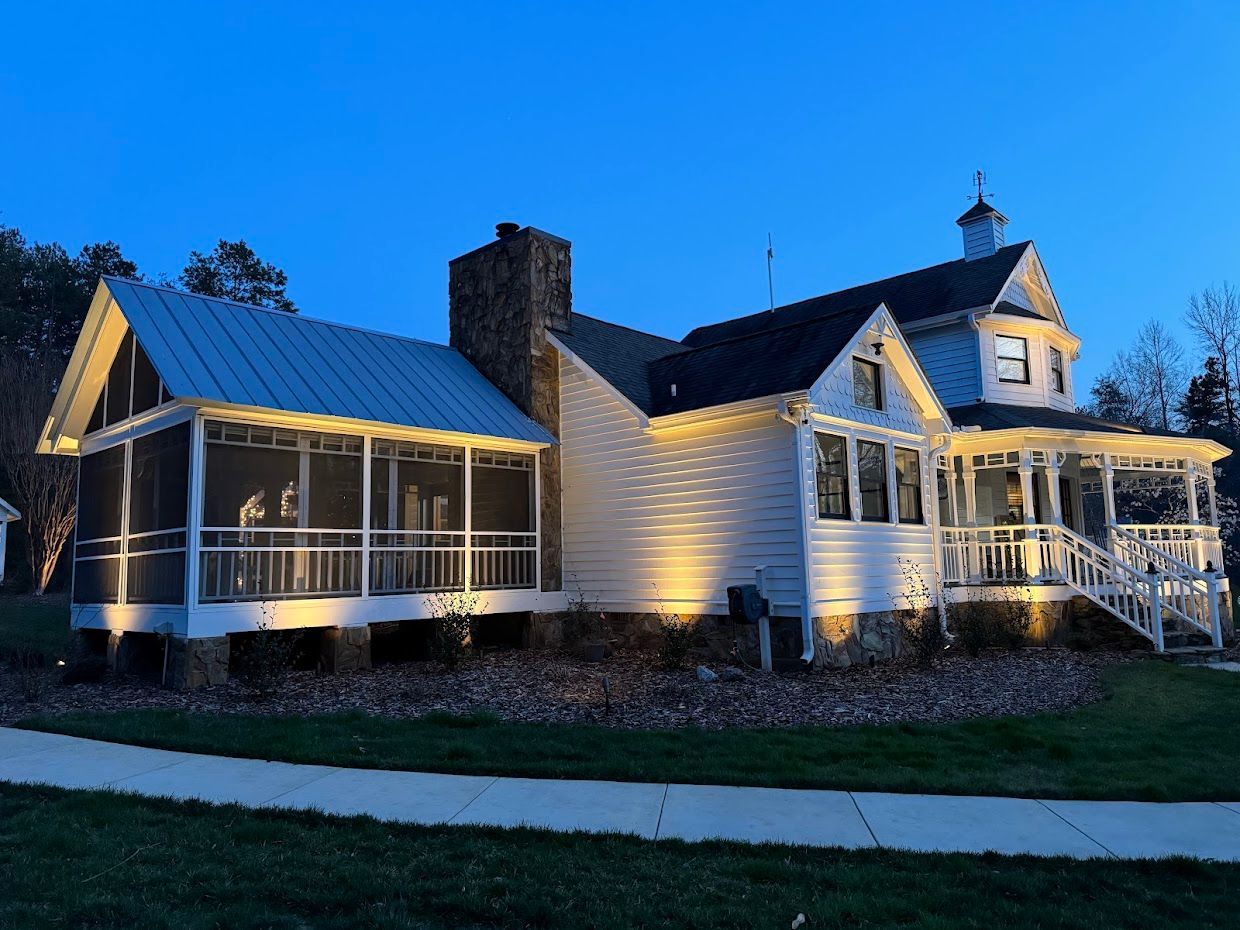 White house with porch and chimney lit at dusk.