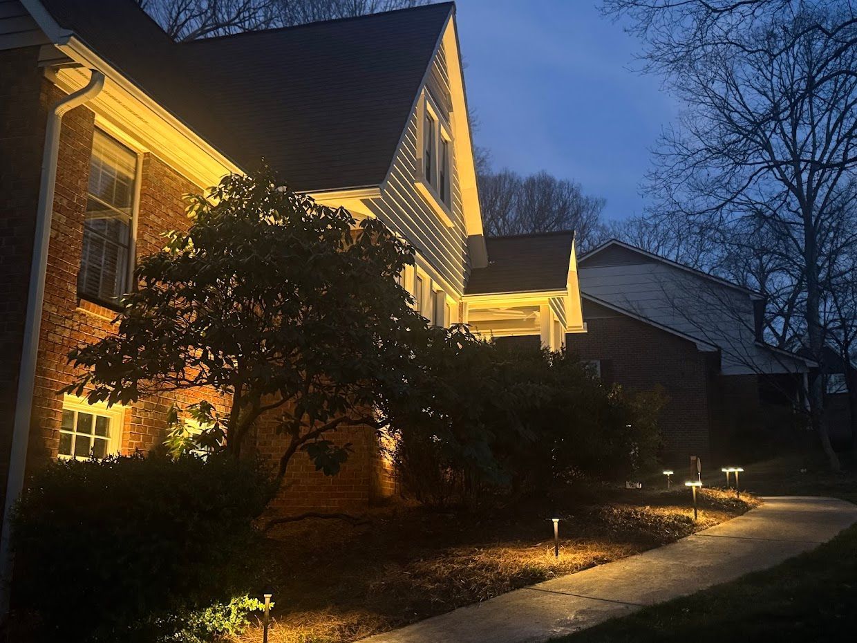 Lit house exterior at dusk with path lights illuminating a walkway, creating a warm ambiance.