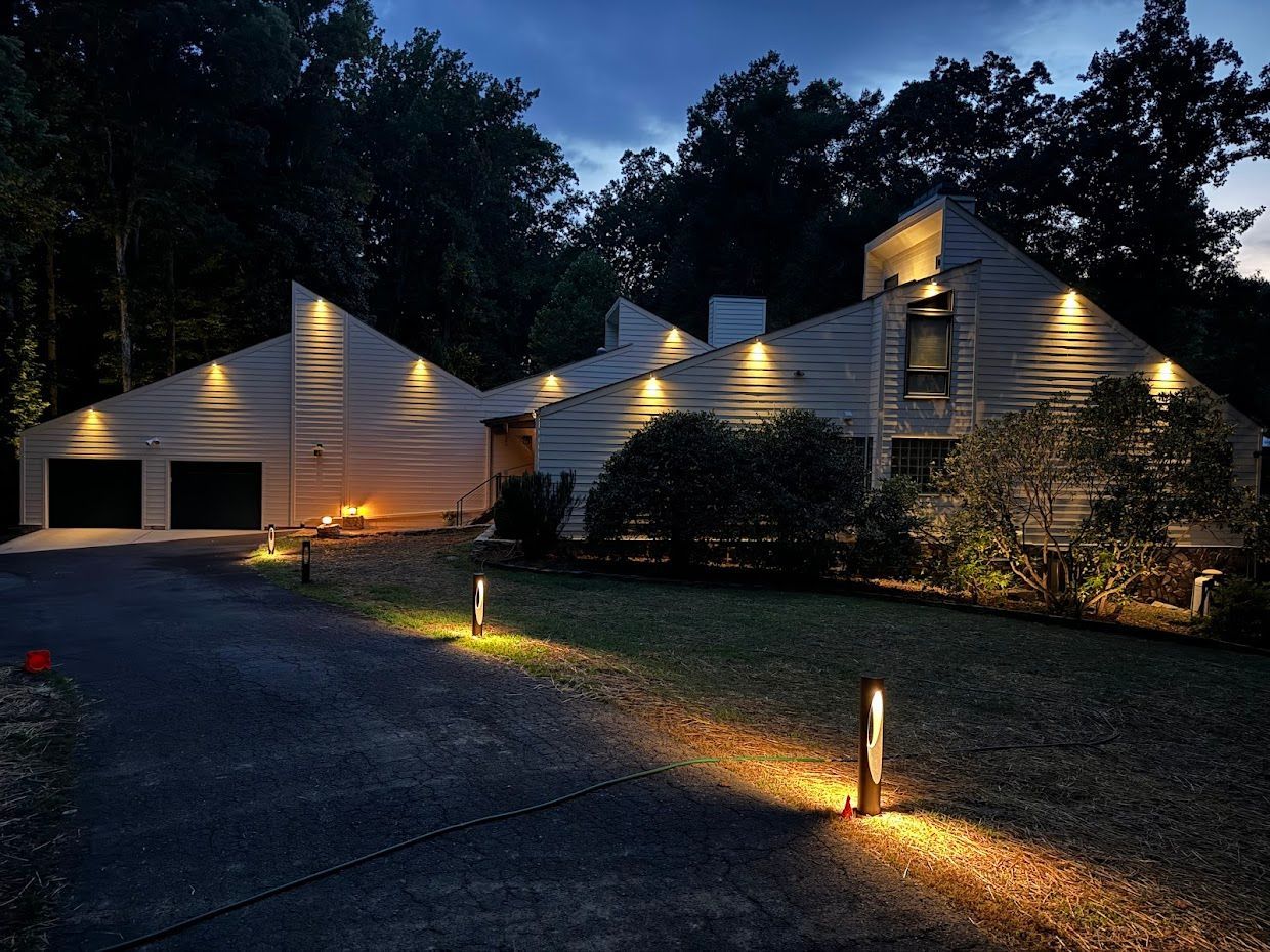 Night view of a house with illuminated exterior lights and a dark driveway.