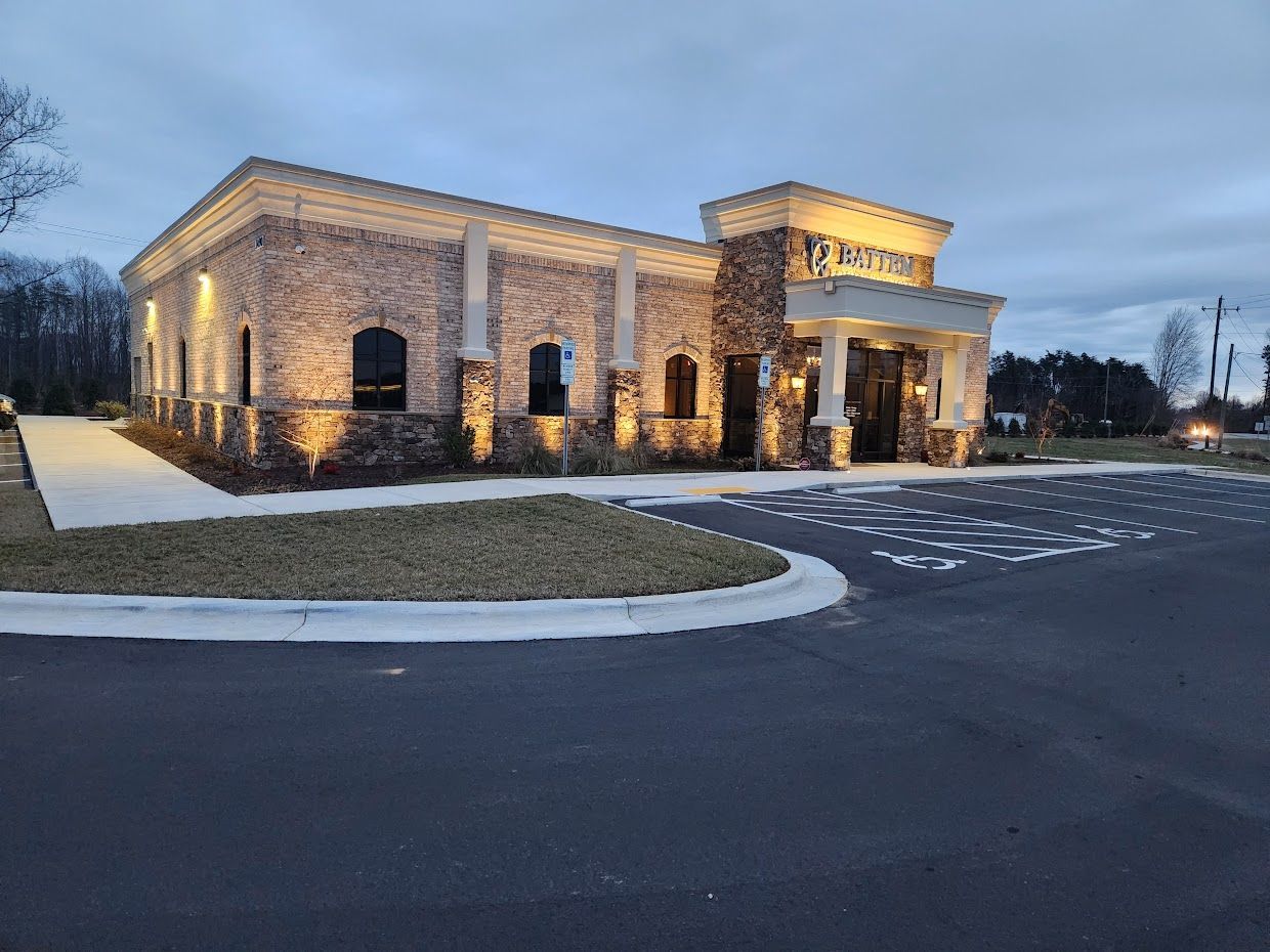 Brick building with stone accents; driveway in front, lawn on the side, dusk sky.