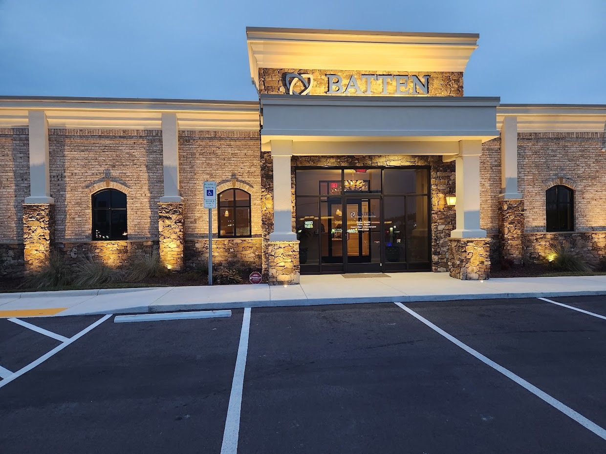 Restaurant exterior with beige brick facade, glass doors, and parking lot at dusk.