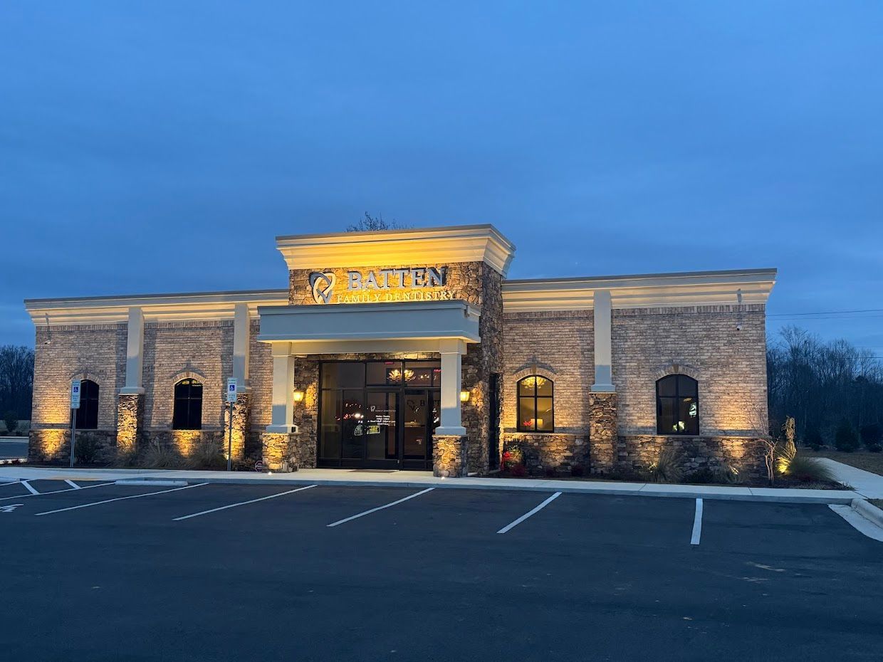 Brick building at dusk with illuminated exterior, entrance under a stone arch.