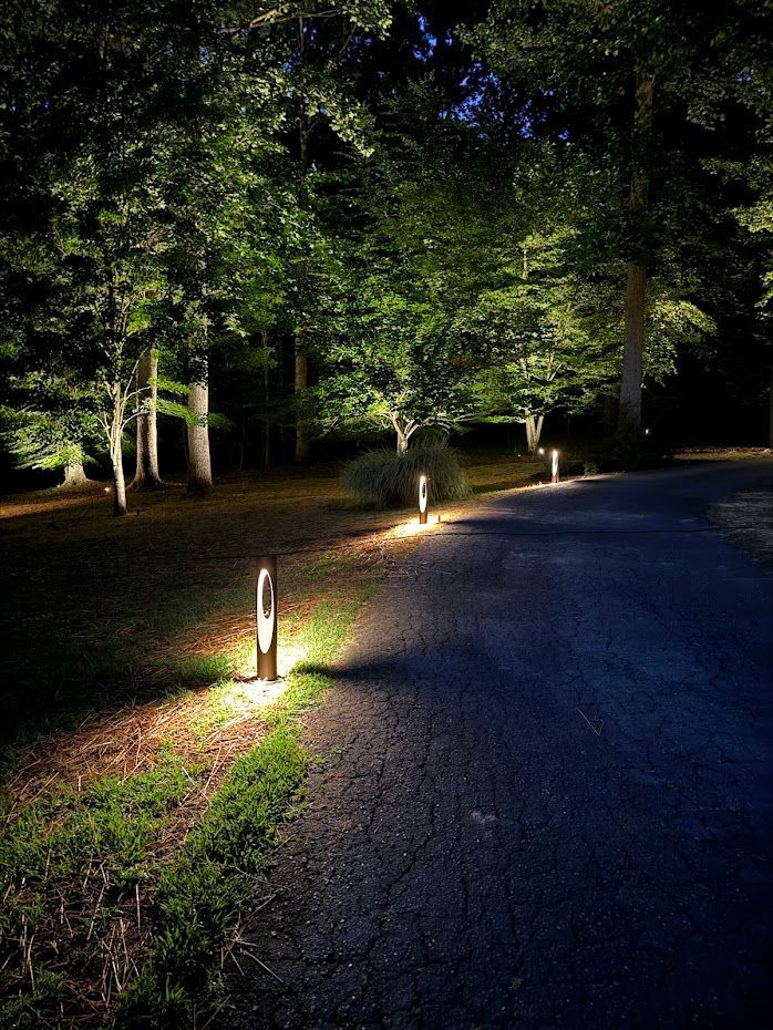 Pathway illuminated at night by modern bollard lights, trees in background.