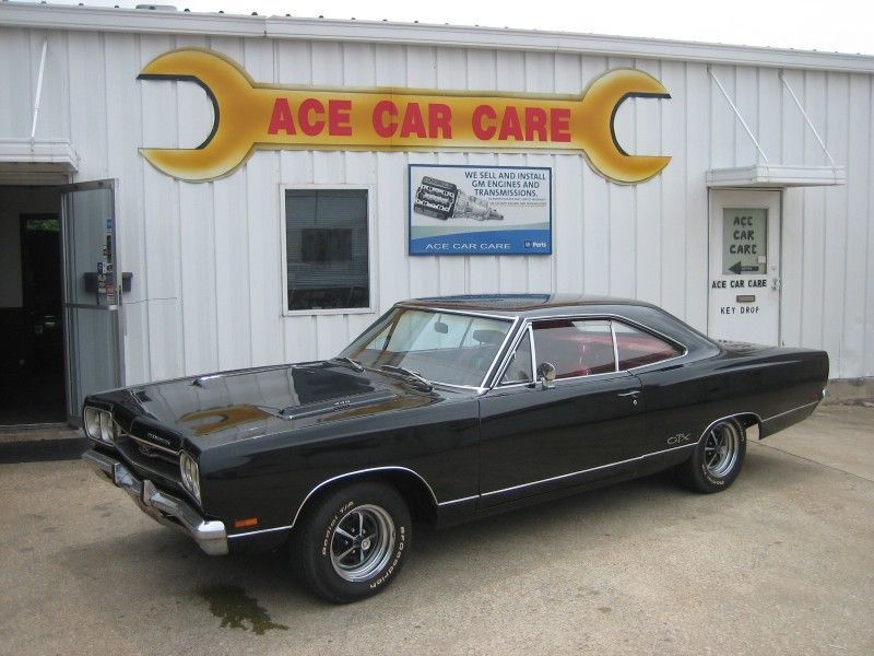 A black car is parked in front of ace car care