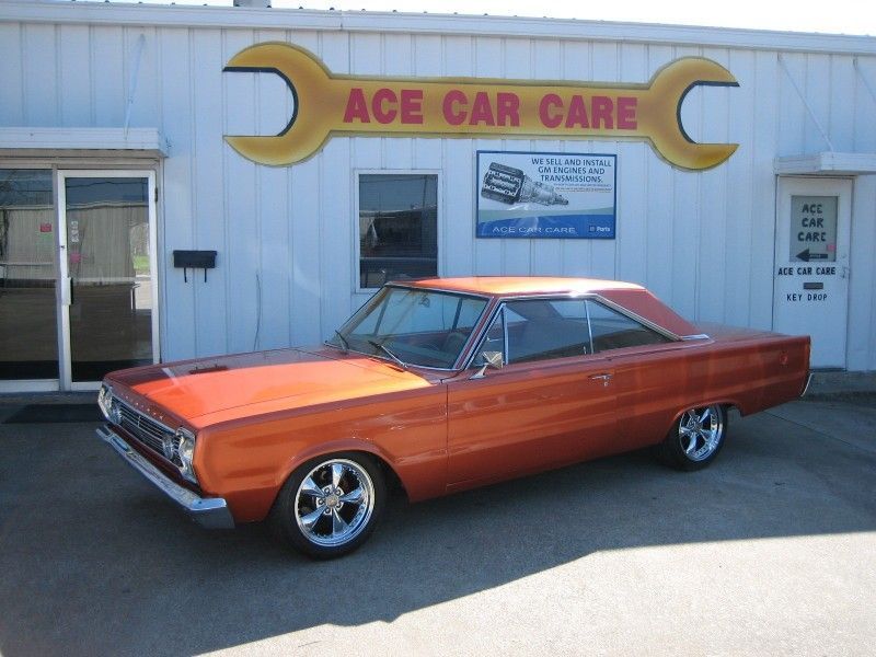 An orange car is parked in front of ace car care