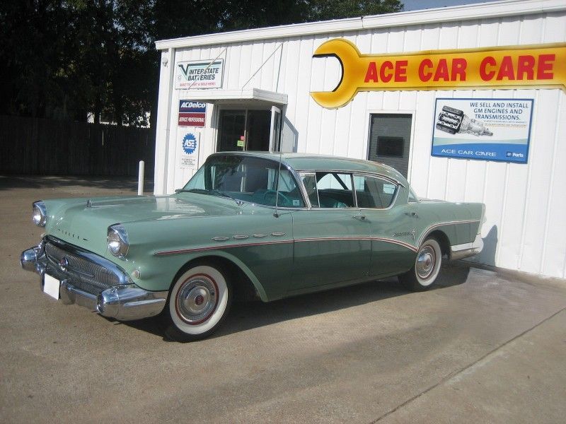 A green car is parked in front of an ace car dealership