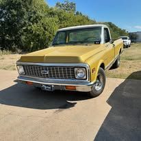 A yellow chevrolet truck is parked in a driveway.