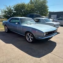 A blue car is parked in a parking lot next to a white car.