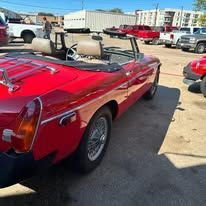 A red convertible sports car is parked in a parking lot.
