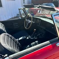 The interior of a red convertible car with black seats and a steering wheel.