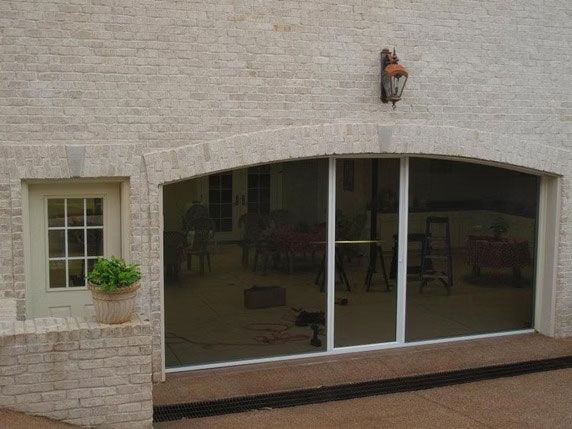 A stone building exterior with an arched sliding glass door, a small side door with a window, and an outdoor light fixture.