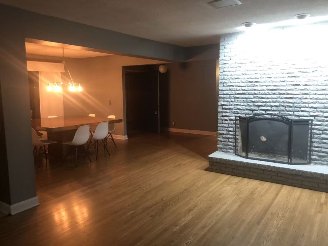 A dining area with a table and chairs, visible next to a large fireplace with a gray stone-textured wall.