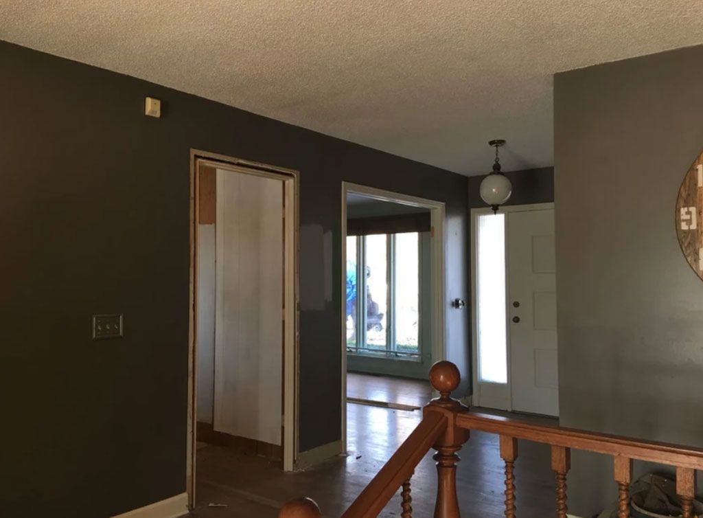 An interior view showing a staircase railing leading into a hallway with dark brown walls, doorways, and natural light.