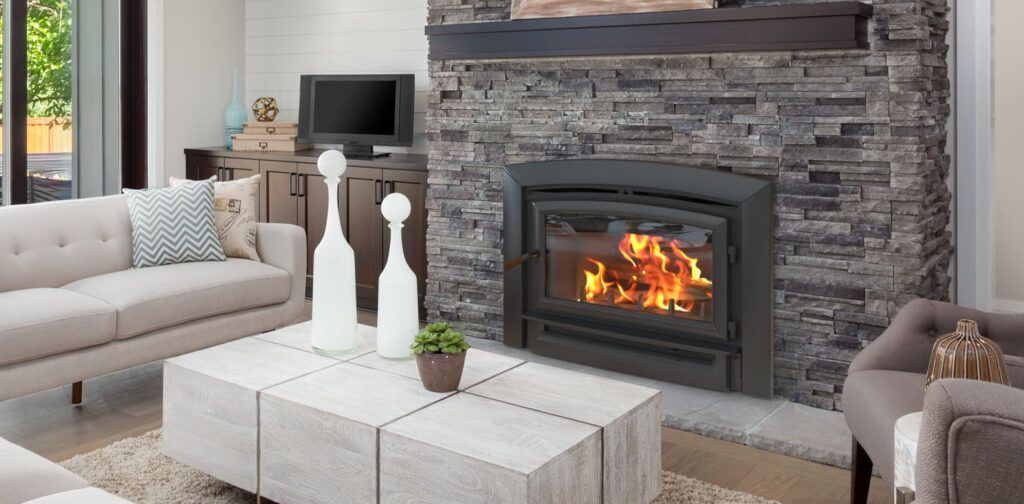 Living room with a lit fireplace. A light-colored sofa and stone-covered fireplace surround