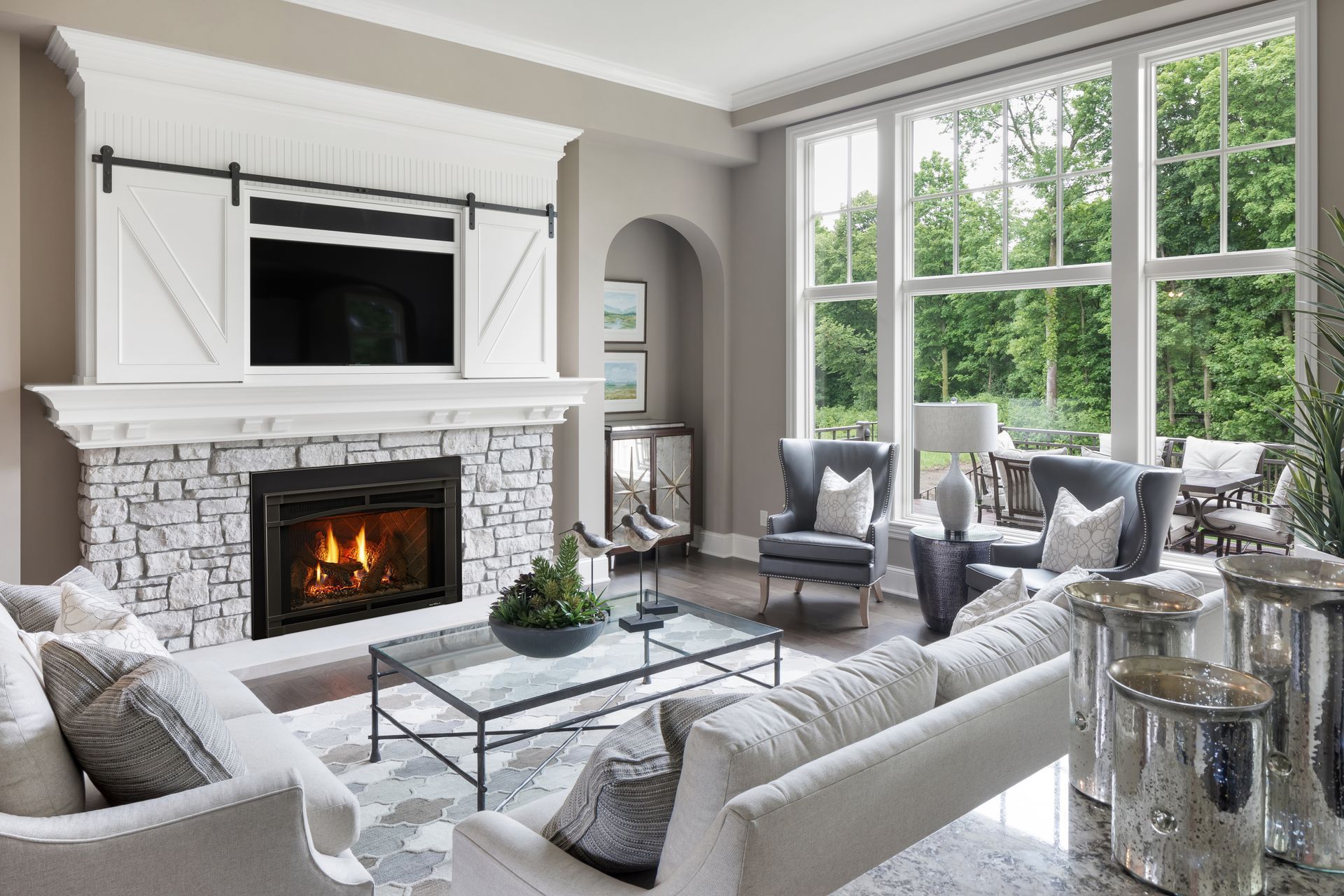 Living room with fireplace, white sofas, large windows, and outdoor view.