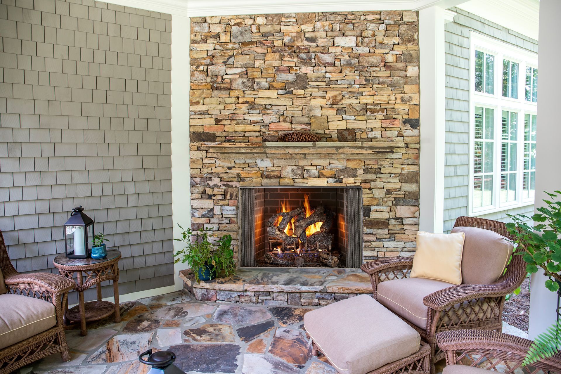 Cozy outdoor fireplace with stone surround and burning fire, surrounded by seating.