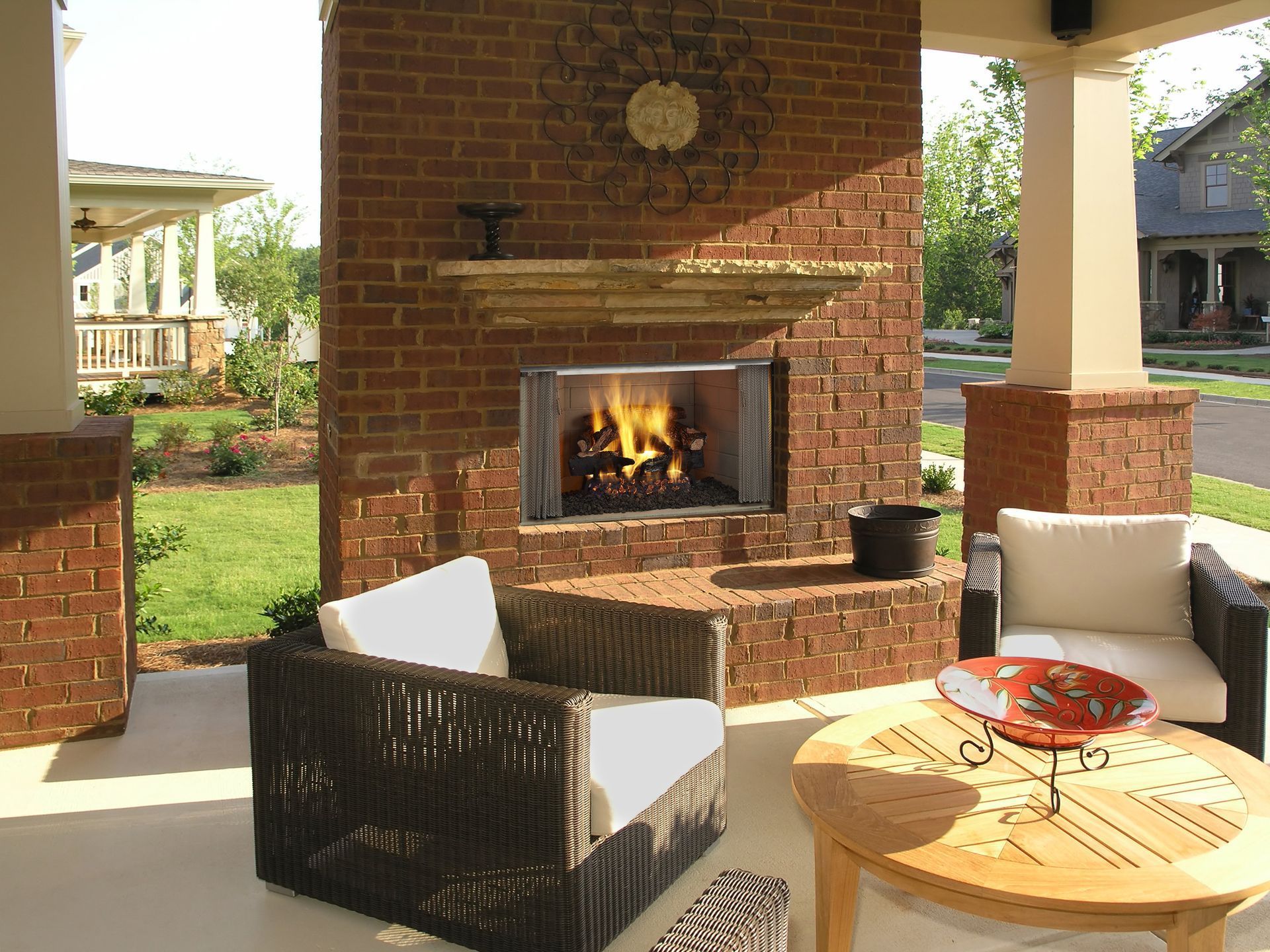 Outdoor brick fireplace with seating area; fire burning, sunny day.