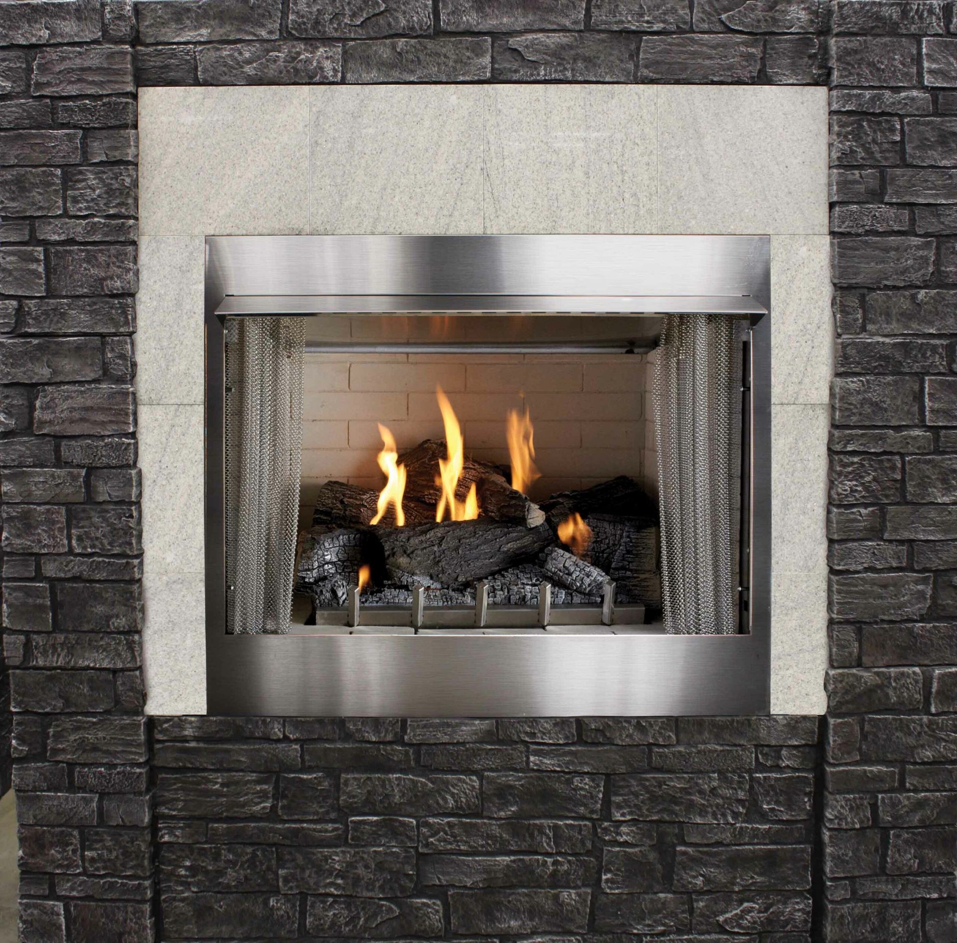 Fireplace with flames and faux logs, set within a gray stone and concrete frame.