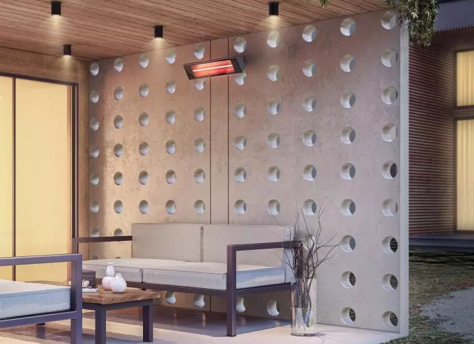 Outdoor seating area with a sofa, perforated wall, and infrared heater.