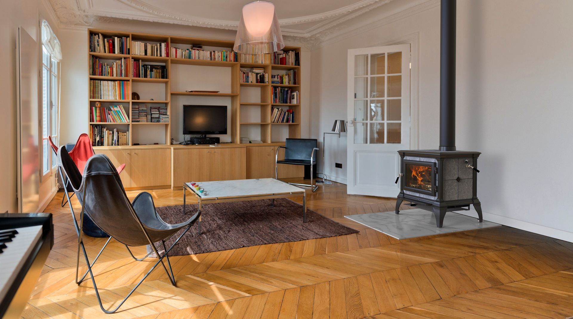 Living room with fireplace, bookshelves, wood floor, modern furniture, and a door.