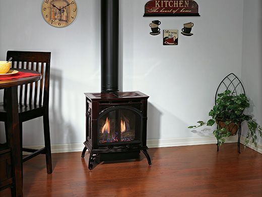Gas fireplace with flames, dark metal pipe, and wood floor in a kitchen setting.
