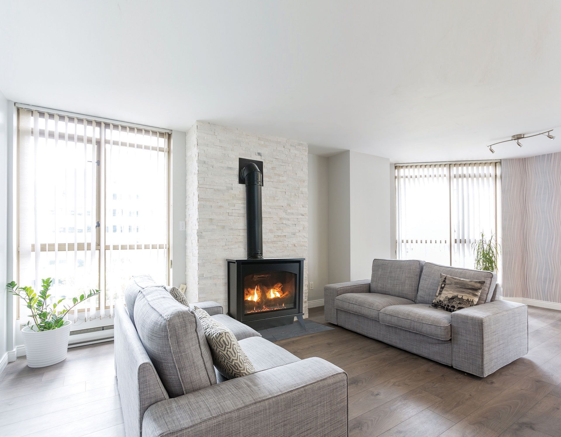 Living room with gray sofas, fireplace, and large windows.