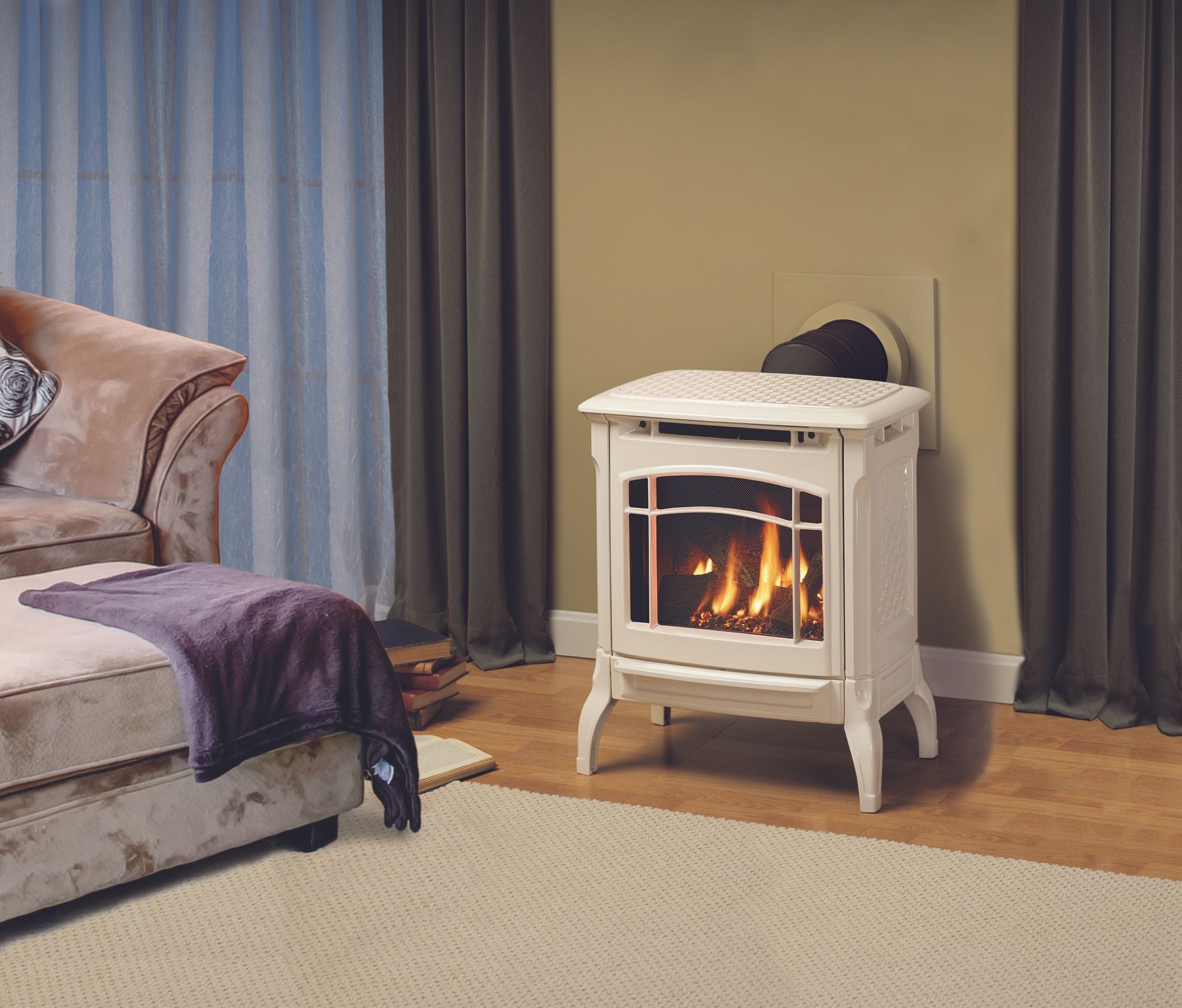 Cream-colored gas fireplace in a living room, flames visible. Beside a couch with a purple blanket.