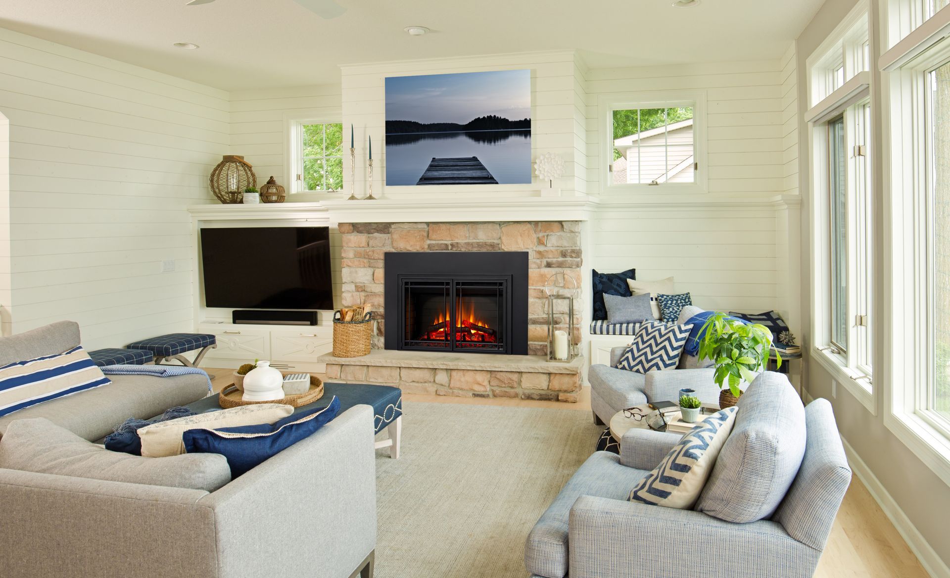 Living room with fireplace, stone mantel, and two gray couches. Lake picture above fireplace.