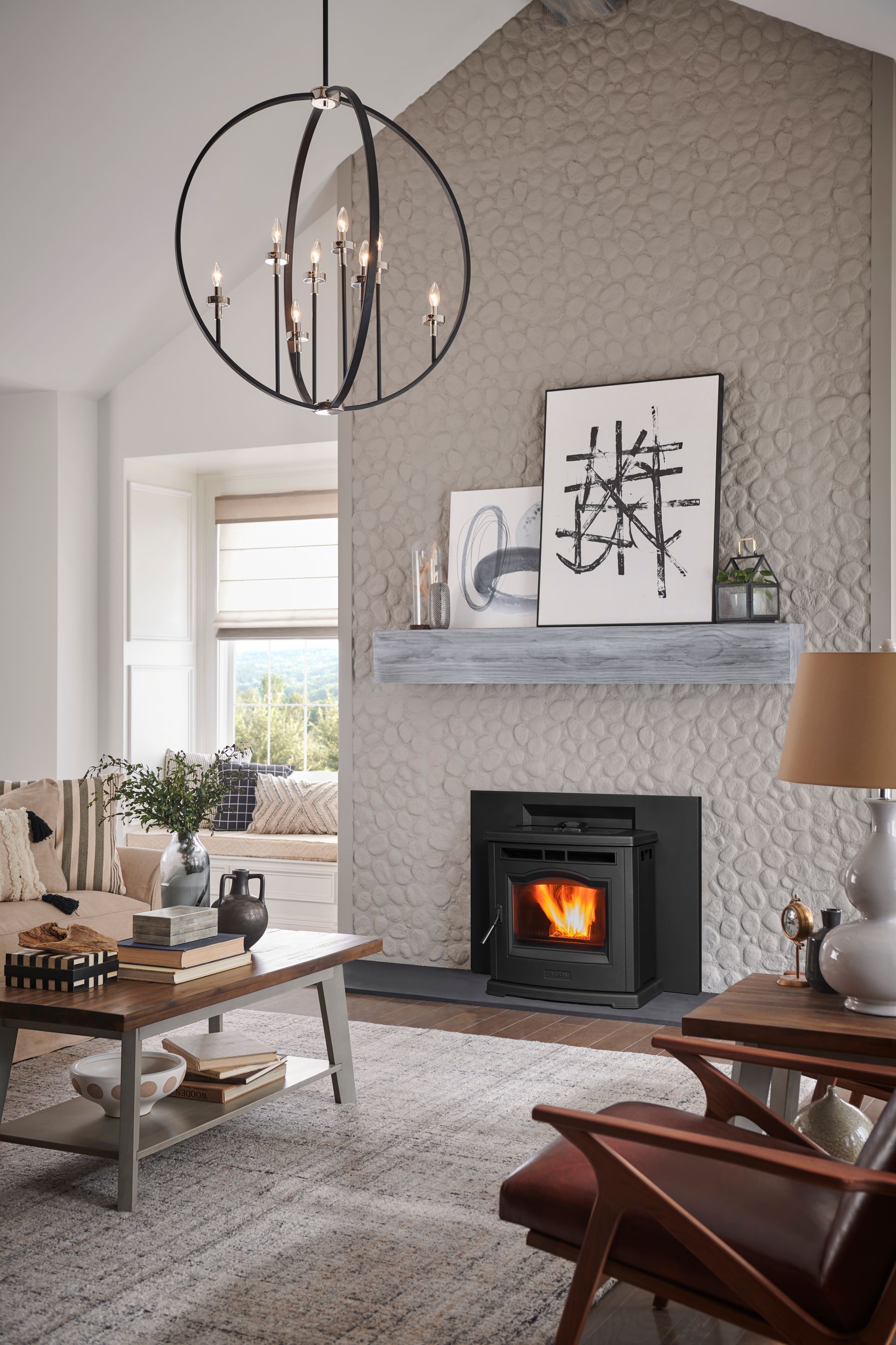 Cozy living room with fireplace, gray textured wall, modern chandelier, artwork, and neutral furnishings.