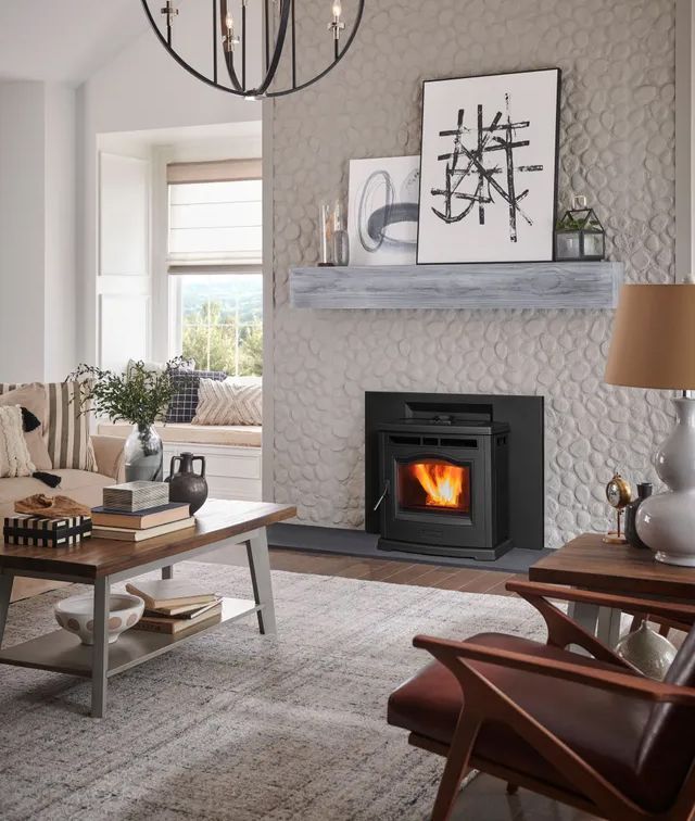 Cozy living room with fireplace, gray textured wall, modern chandelier, artwork, and neutral furnishings.