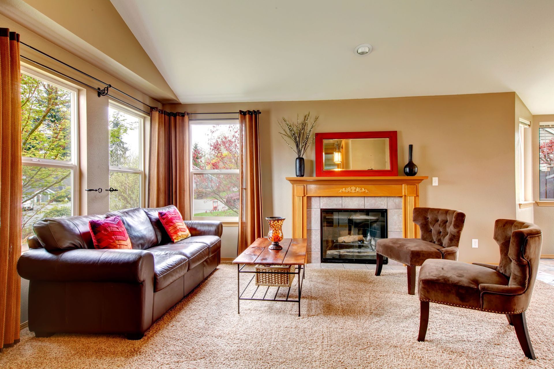 Living room with fireplace, brown leather sofa, and two armchairs; neutral tones.