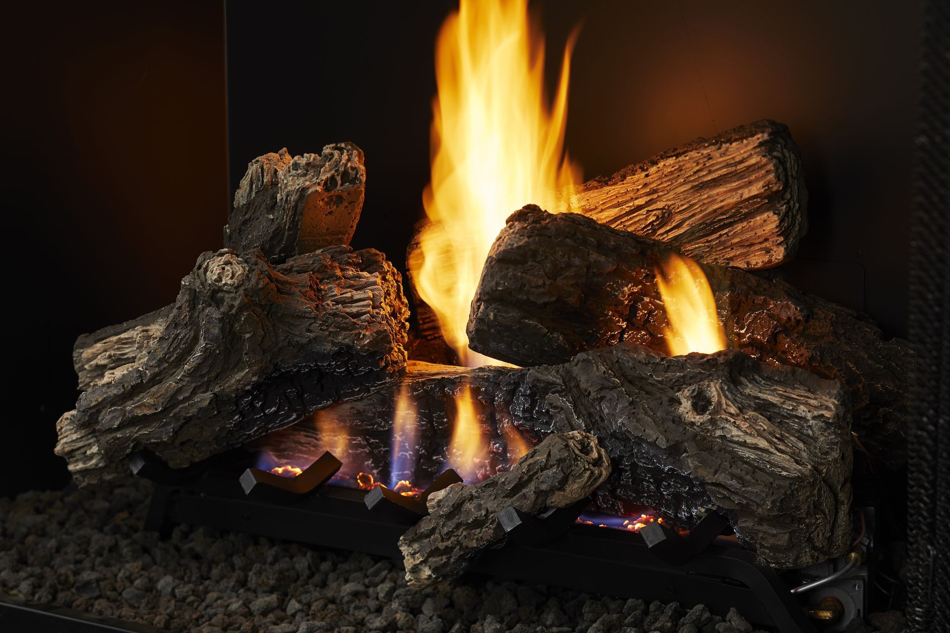 Gas fireplace with burning logs and tall orange flames.