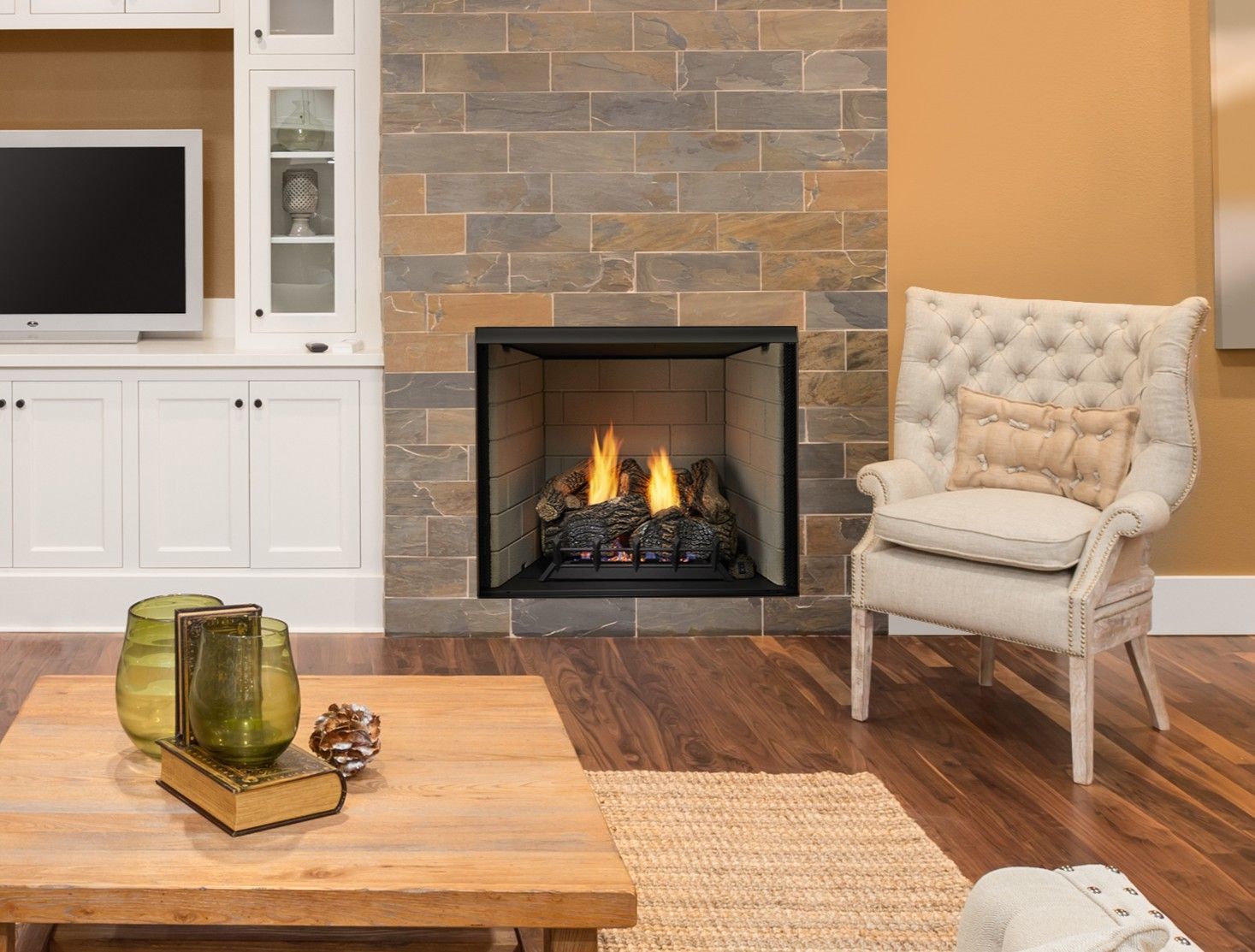 Fireplace with stone surround, lit flames, cozy chair in living room.