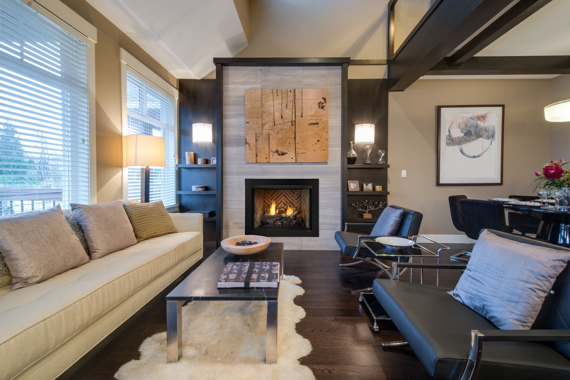 Living room with fireplace, cream sofa, black chairs, artwork, and modern decor.