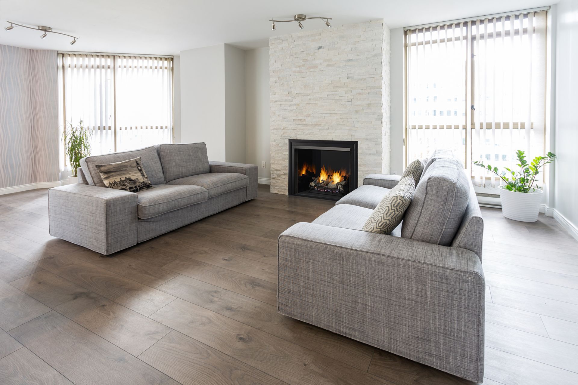 Living room with gray sofas, fireplace, and large windows.