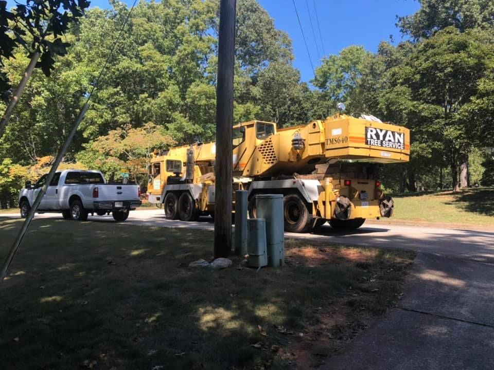 A yellow crane is parked on the side of the road next to a white truck.