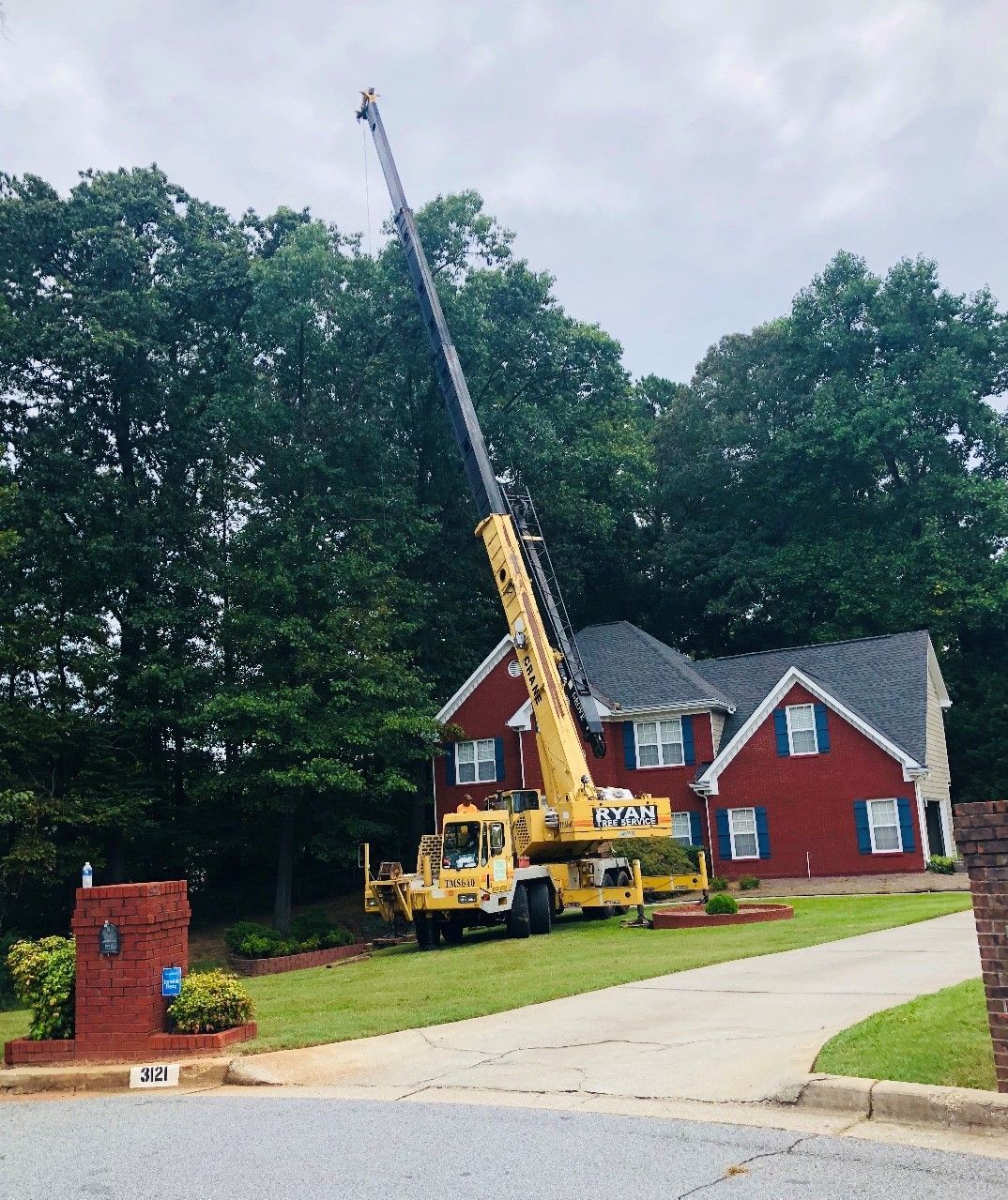A yellow crane is parked in front of a red house