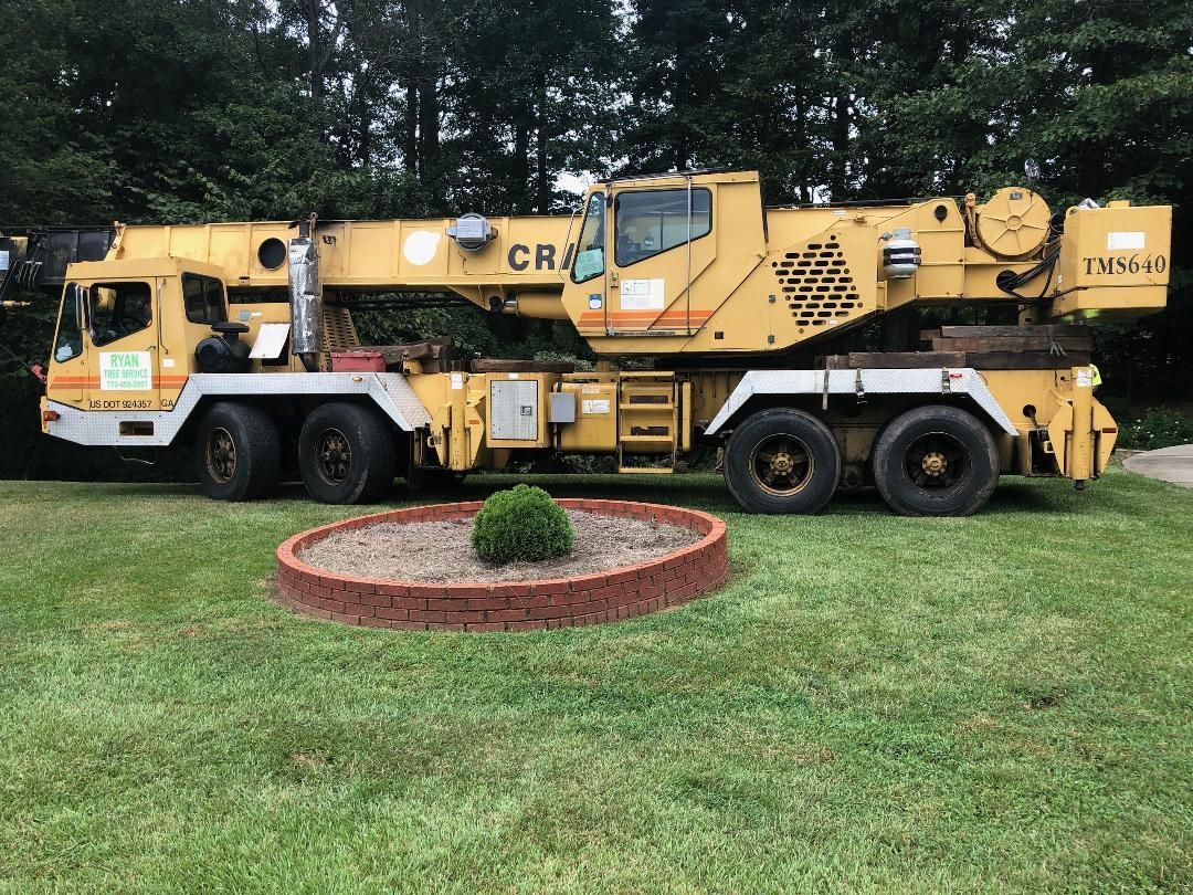 A large yellow crane is parked in a grassy field.