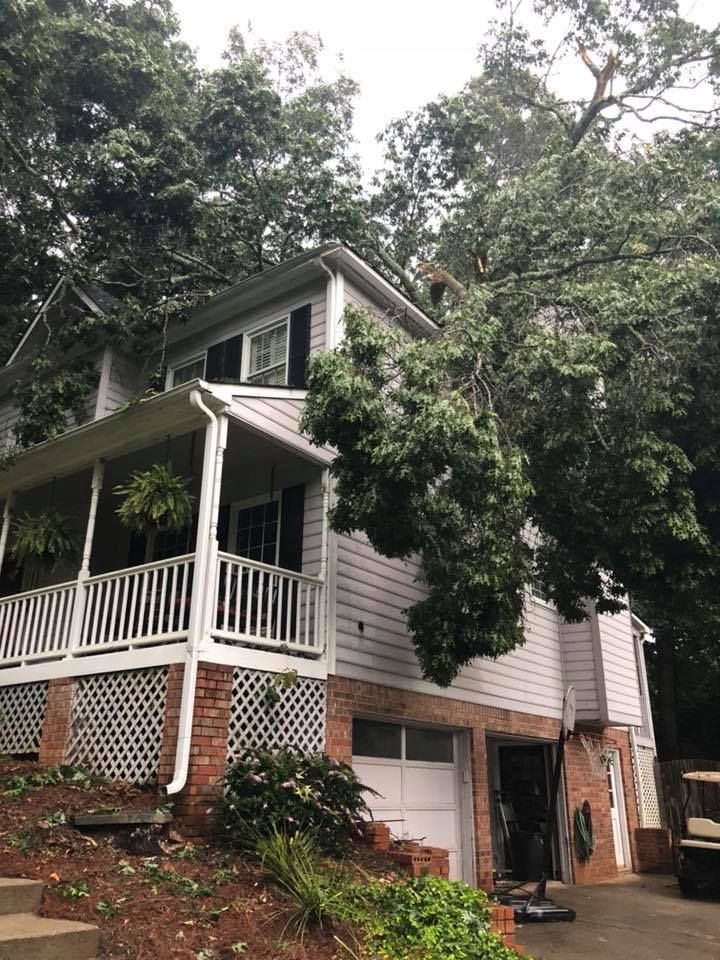 A house with a porch and a garage is surrounded by trees.