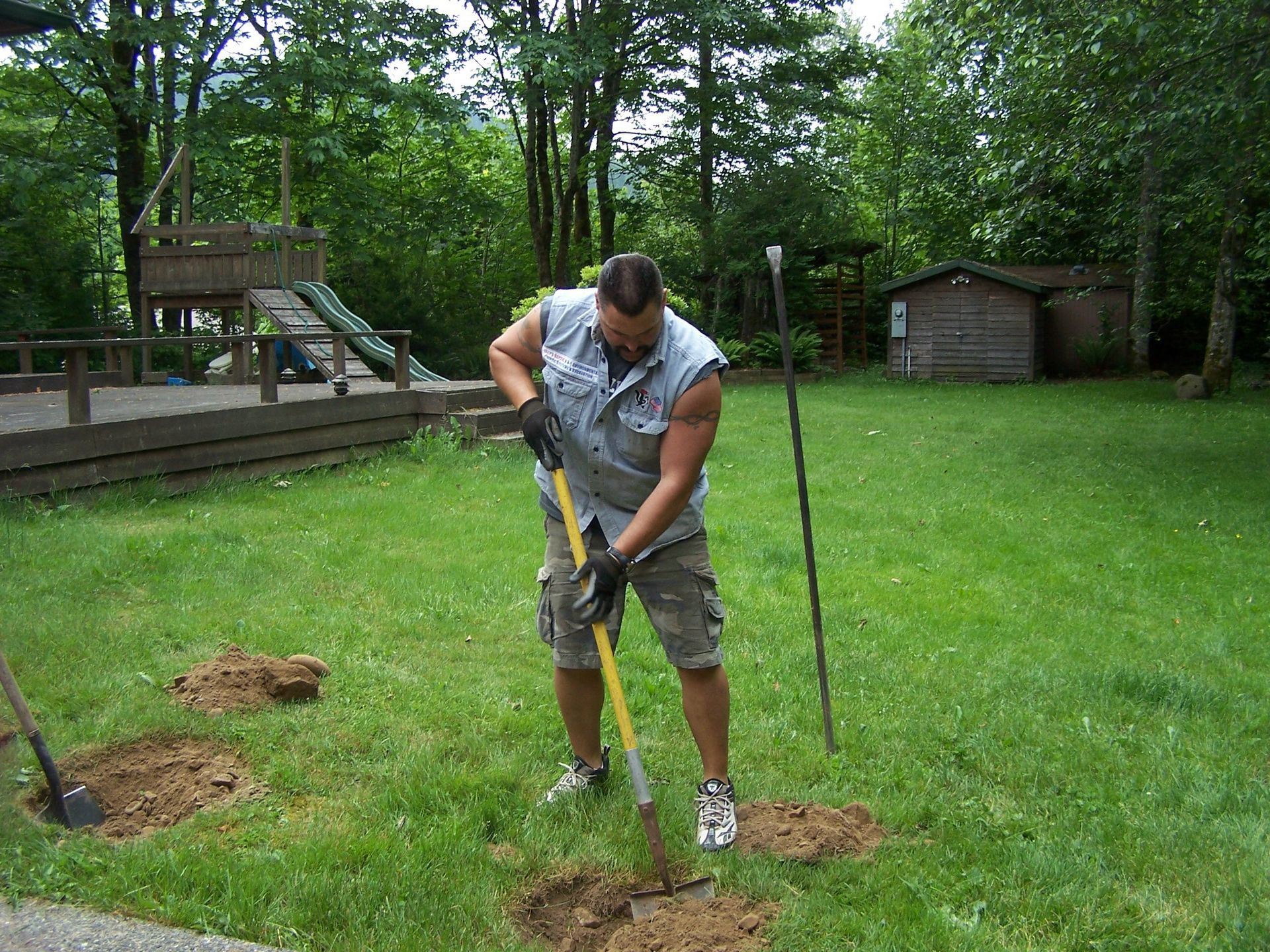 A man is digging in the grass with a shovel
