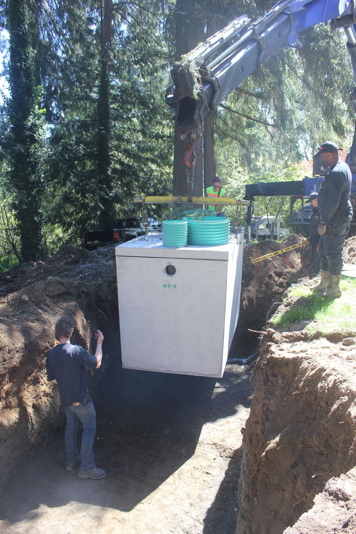 A crane is lifting a large white box into a hole.