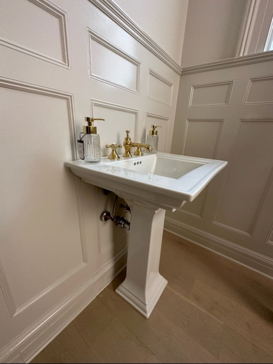 A bathroom with a pedestal sink and soap dispensers