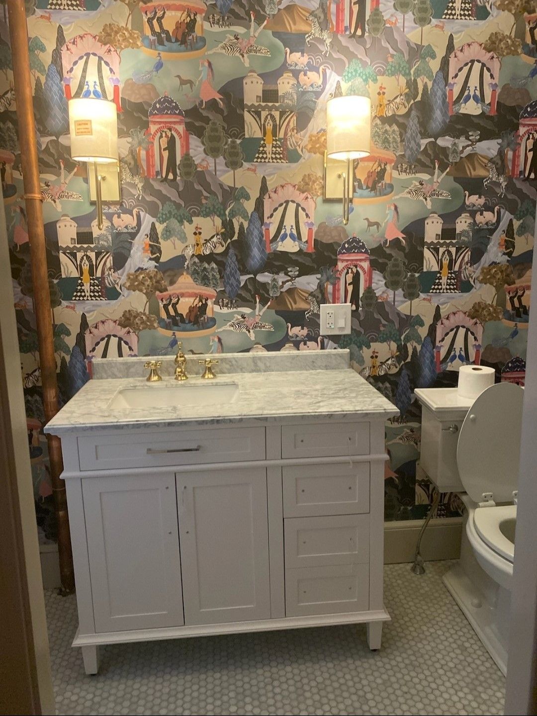 A bathroom with a sink , toilet , and wallpaper