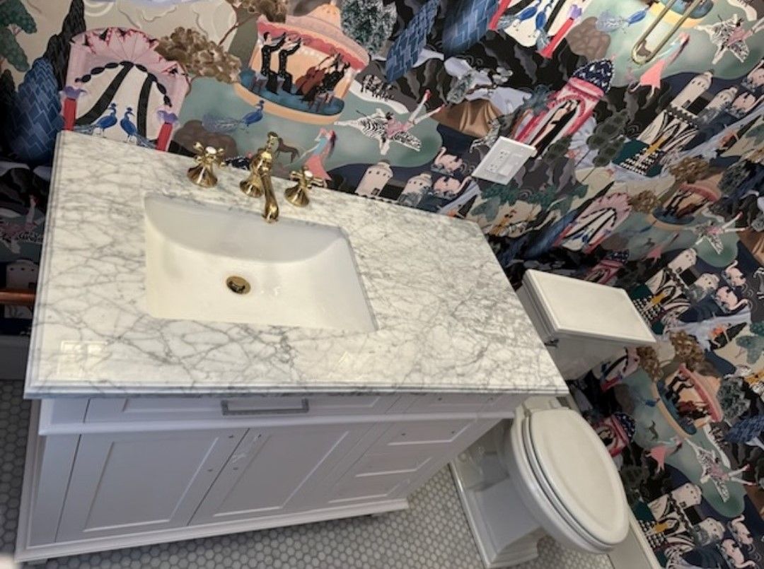 A bathroom with a sink and toilet with a collage of pictures on the wall