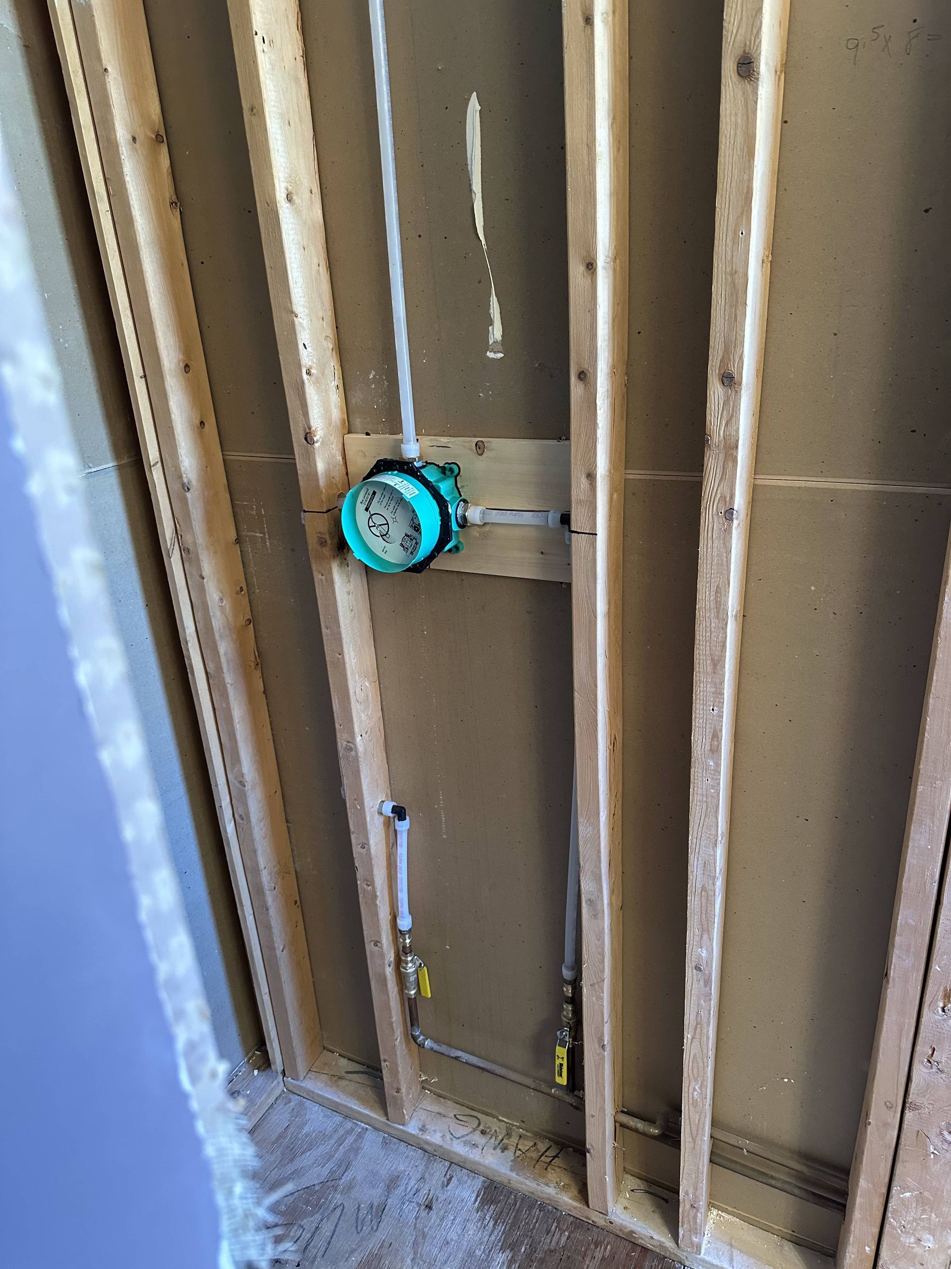 A pipe is being installed in a wooden wall.